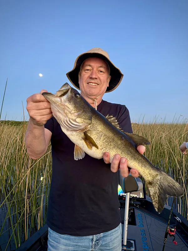 Happy man wearing fisher's hat holding his catch